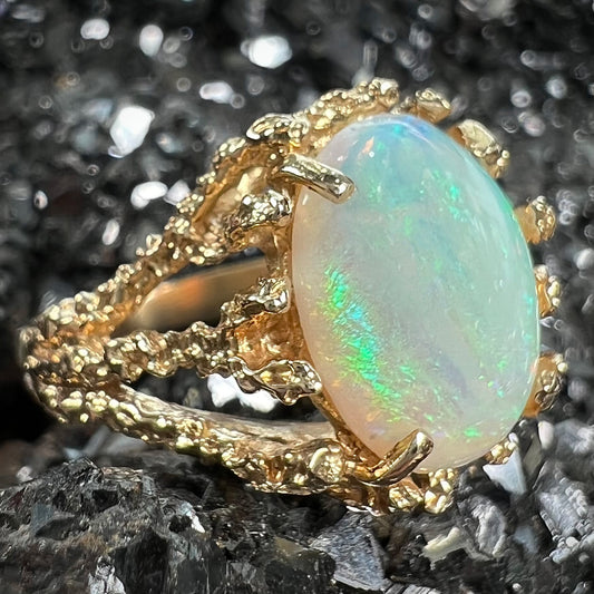 A yellow gold solitaire engagement ring set with an oval cabochon cut white crystal opal.