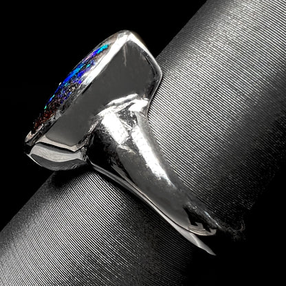 A ladies' white gold ring set with Australian black boulder opal and pear shape blue sapphire.
