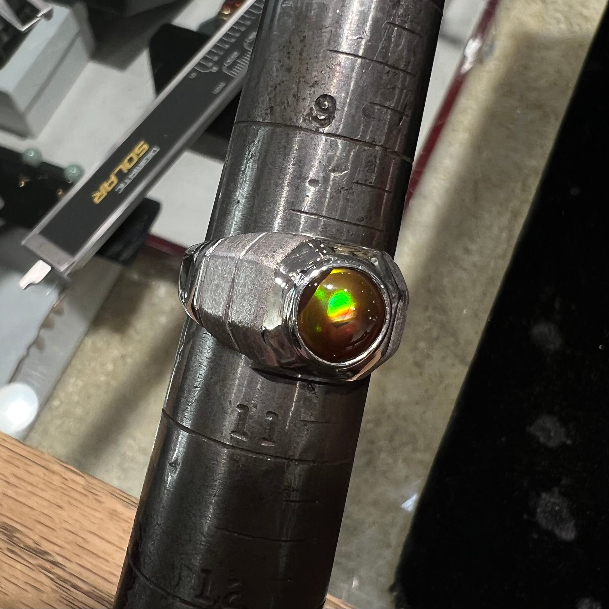 A round cabochon cut red and green fire agate set in a brushed metal white gold men's ring.
