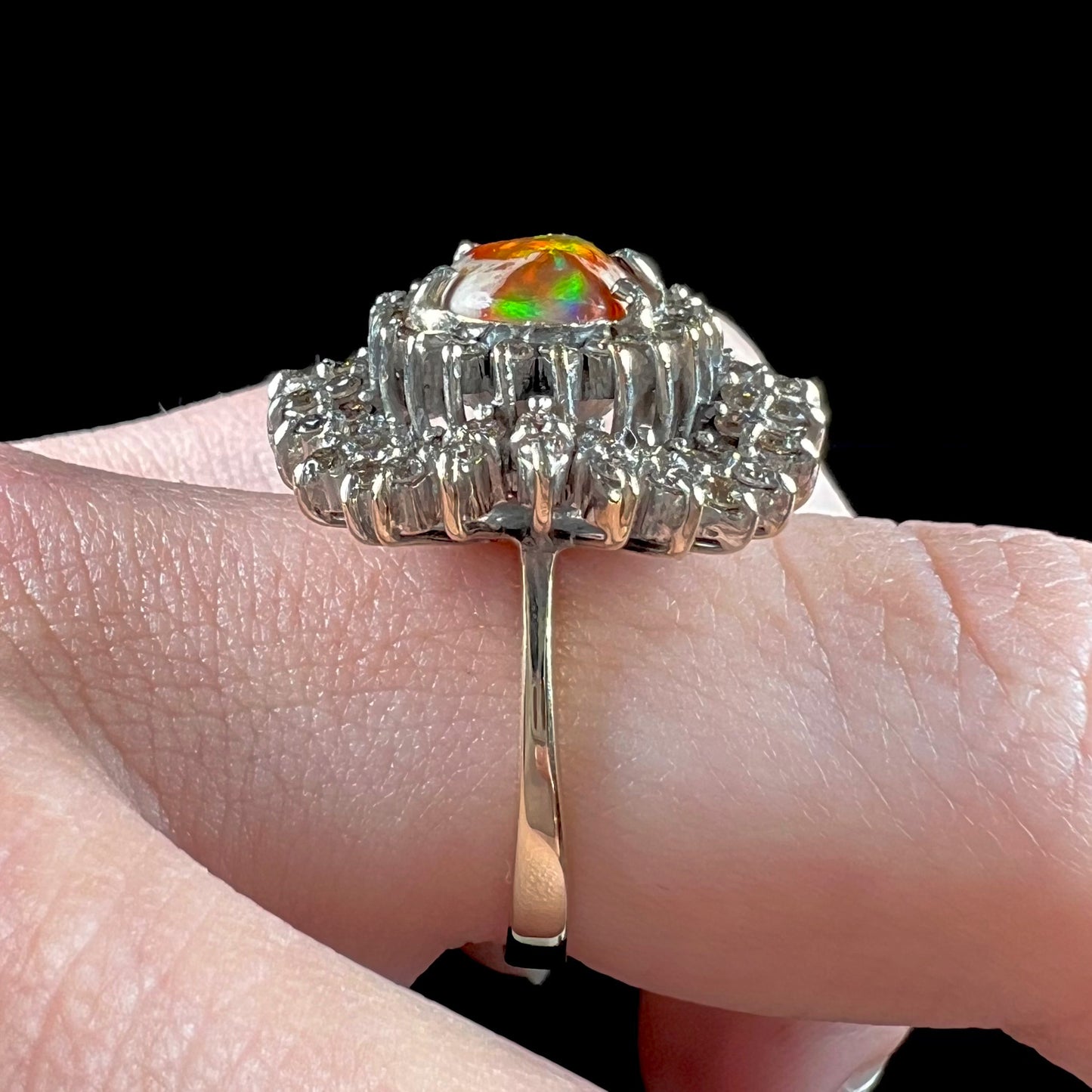 An 18k white gold orange fire opal ring set with a triple halo of diamonds.