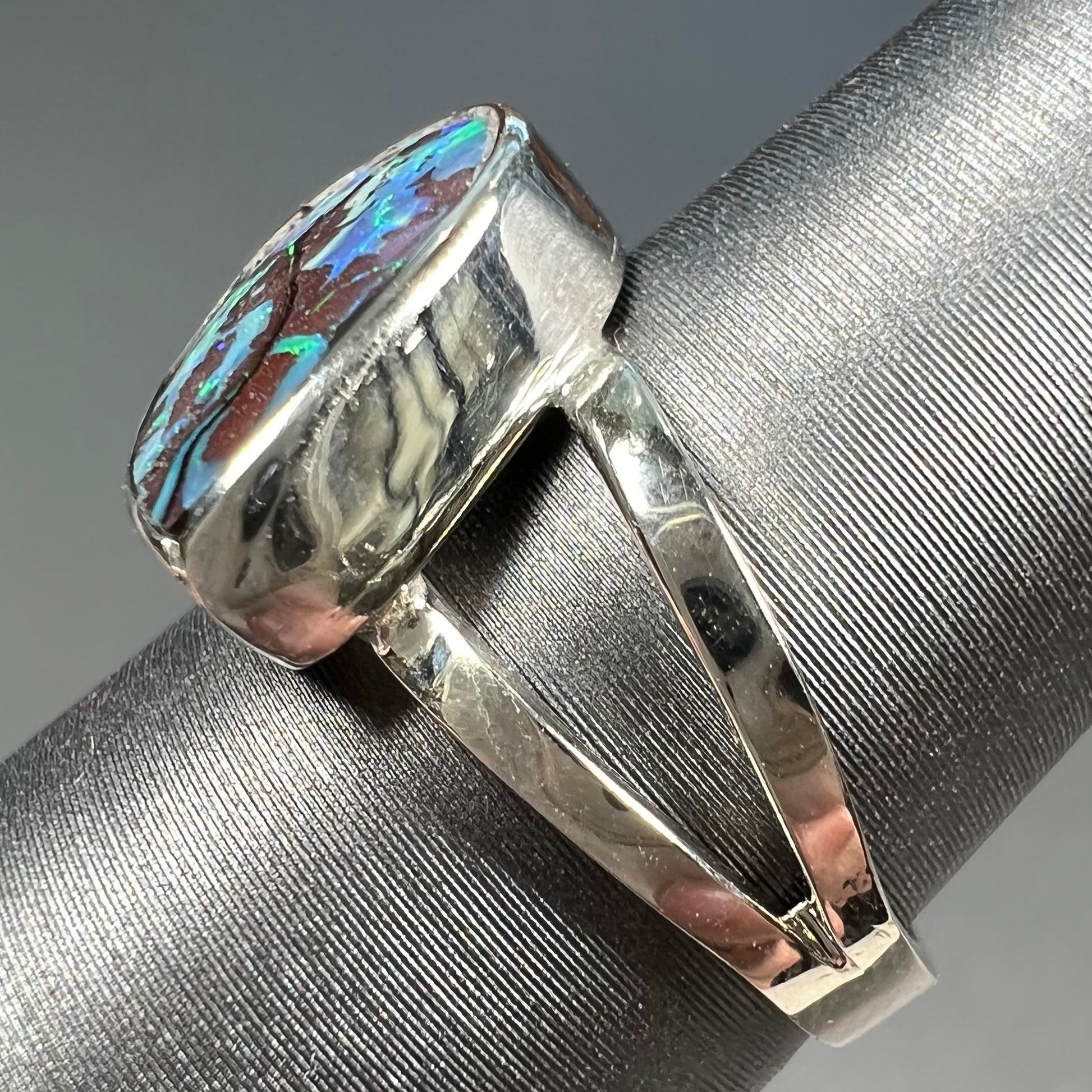 A split shank white gold boulder opal solitaire ring.  The stone has a natural hematite seam that runs through it.