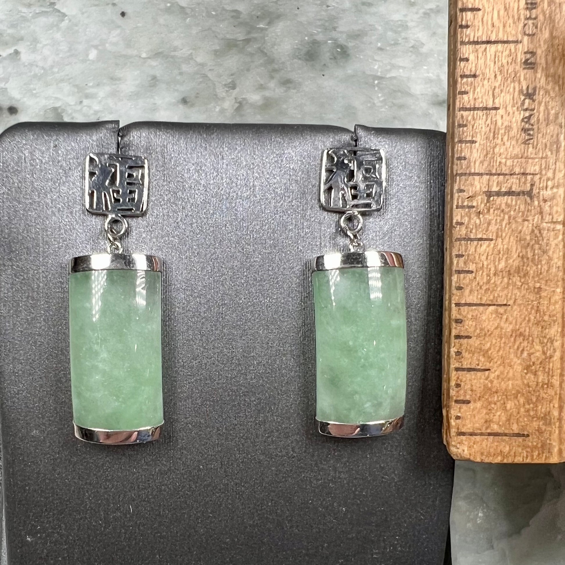 A pair of white gold jadeite dangle earrings with Chinese characters.