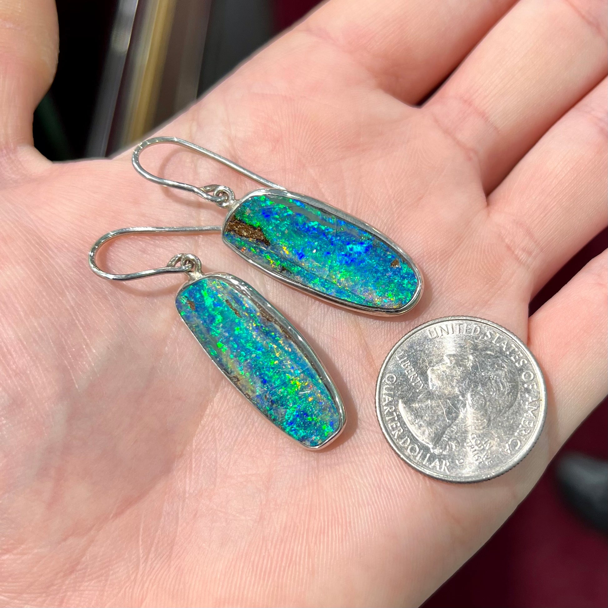 A pair of white gold boulder opal French wire dangle earrings.  The opal is predominantly glimmery blue.