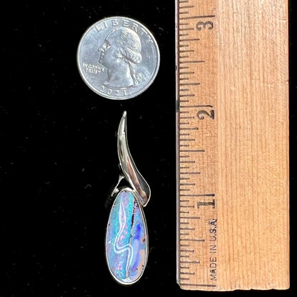 A white gold solitaire pendant set with an Quilpie, Australian boulder opal stone.  The opal shines a rainbow of colors.