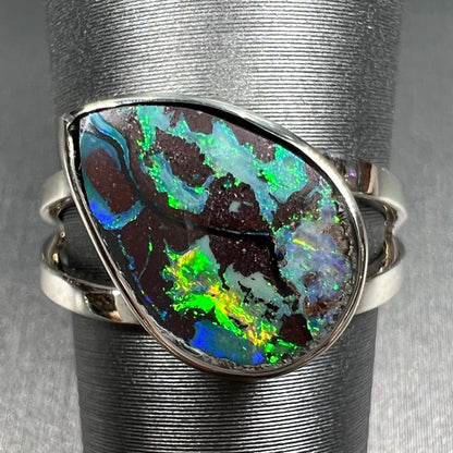 A split shank white gold boulder opal solitaire ring.  The stone has a natural hematite seam that runs through it.