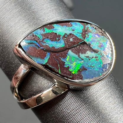 A split shank white gold boulder opal solitaire ring.  The stone has a natural hematite seam that runs through it.