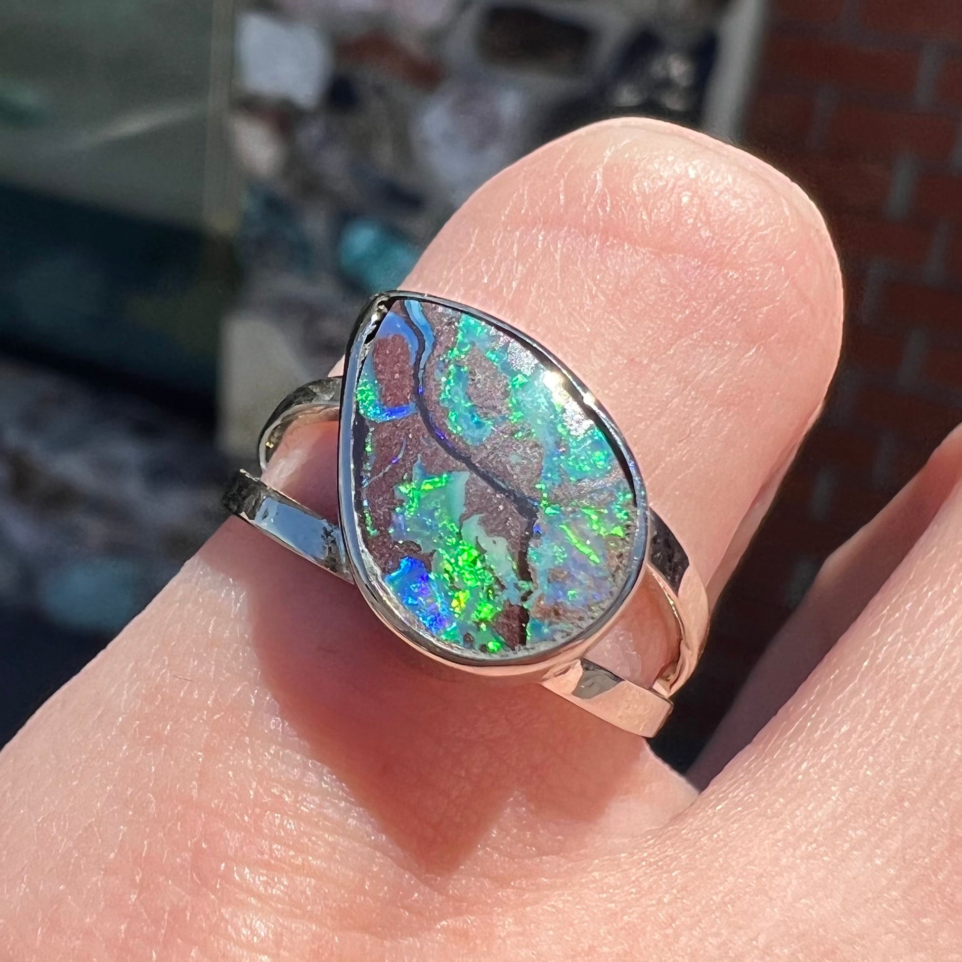 A split shank white gold boulder opal solitaire ring.  The stone has a natural hematite seam that runs through it.