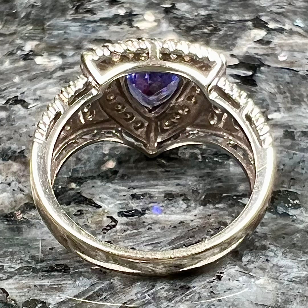 A white gold trillion cut tanzanite ring set with a diamond halo and diamond accents.