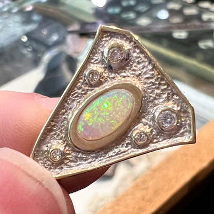 A triangular gold pendant set with five round diamonds and a white crystal opal with green fire.