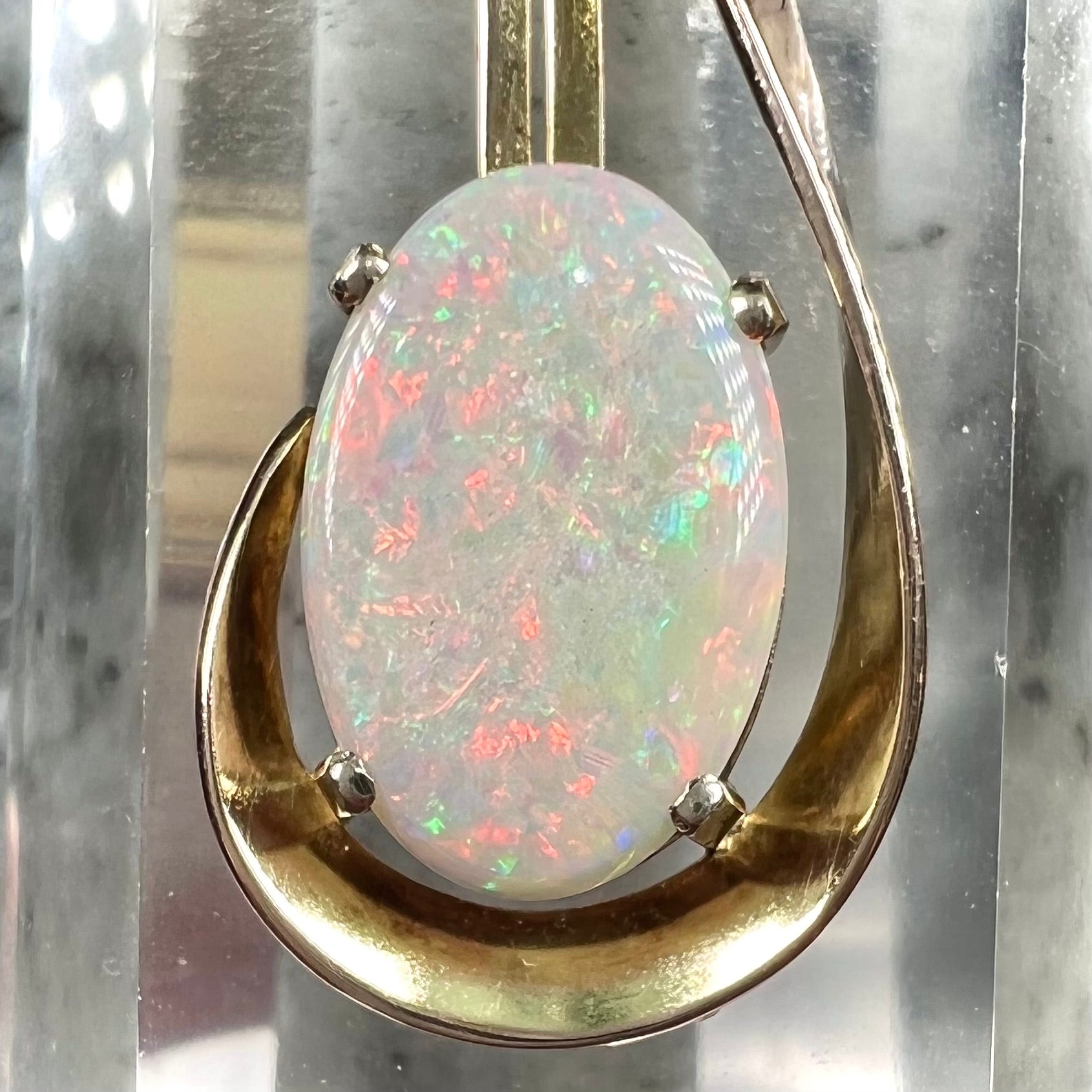 A handmade gold drop pendant set with an oval cabochon cut white crystal opal.