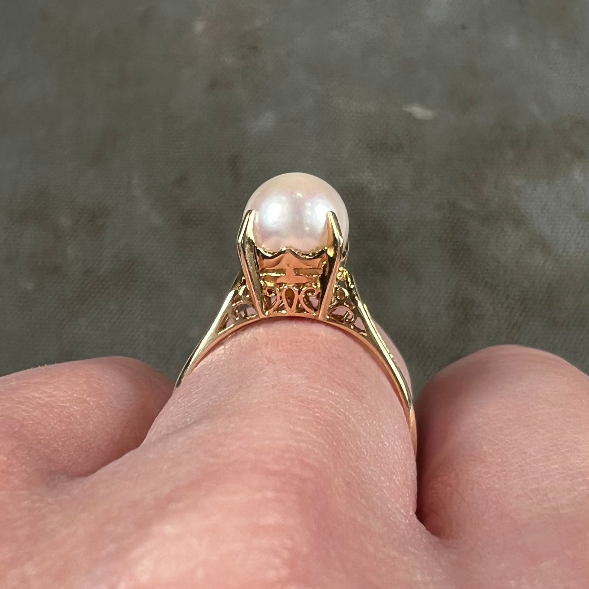 Round white pearl with pink overtones set in a vintage 18k yellow gold ring.
