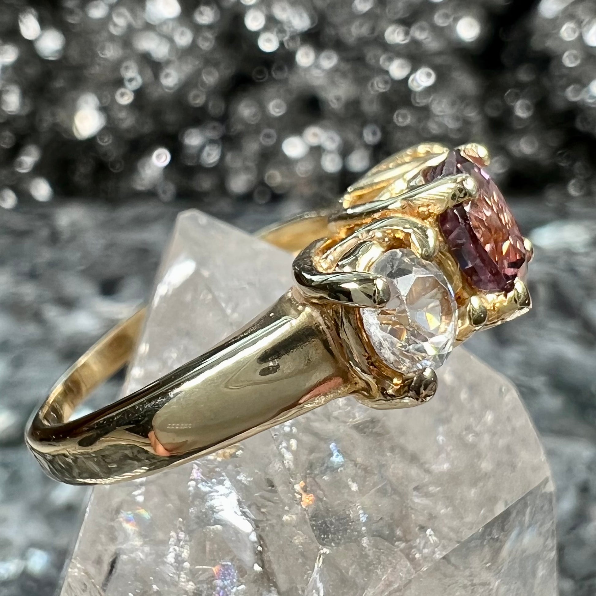 A yellow gold three stone ring set with two round cut white zircons and one cushion cut purple spinel.