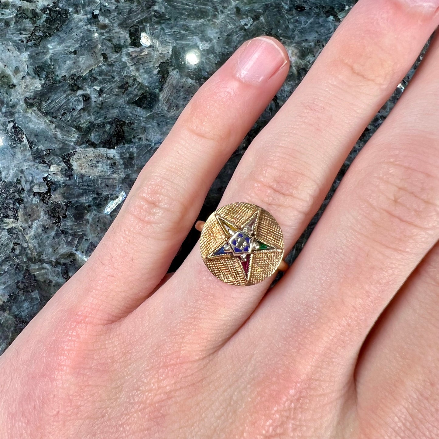 A gold ring set with multicolored synthetic sapphires forming a star with a blue enameled center, symbolizing the Order of the Eastern Star.