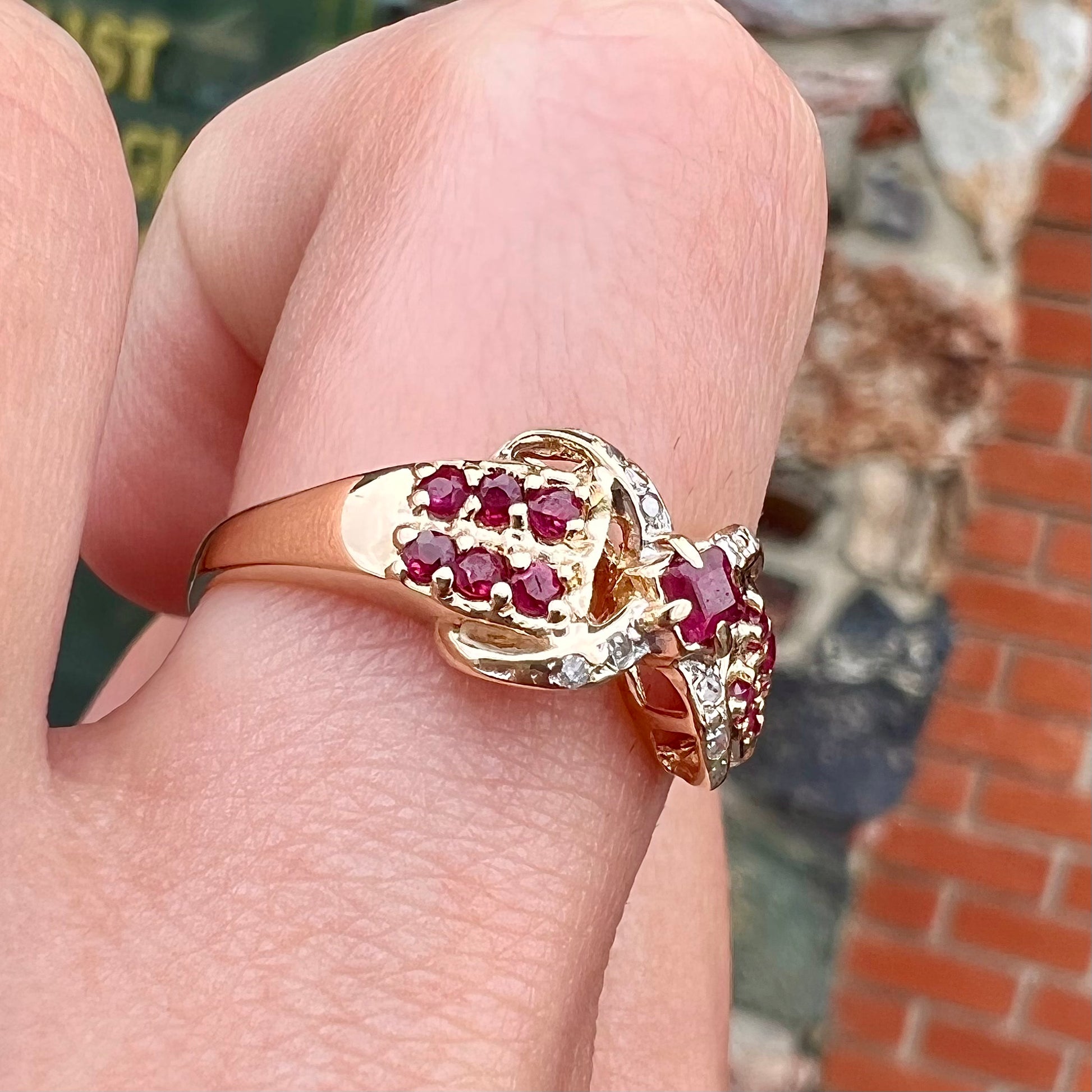 A yellow gold princess cut ruby ring set with round ruby and diamond accents.