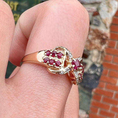 A yellow gold princess cut ruby ring set with round ruby and diamond accents.