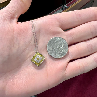 A square shaped necklace set with princess cut yellow and white diamonds in a white gold setting on a white gold chain.