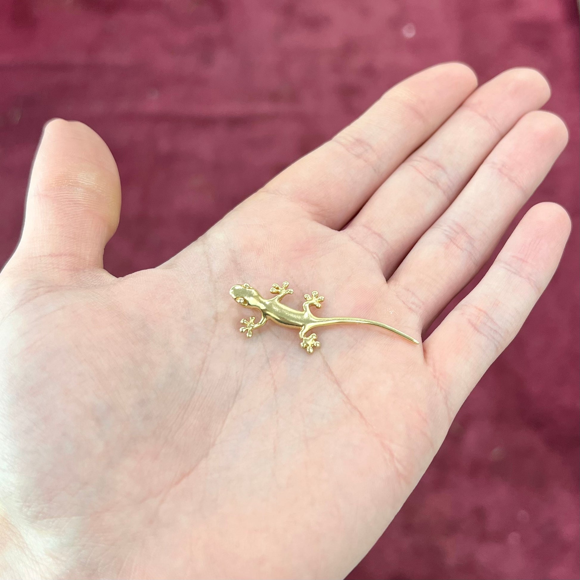 A solid yellow gold gecko lizard pendant with a hidden bail.