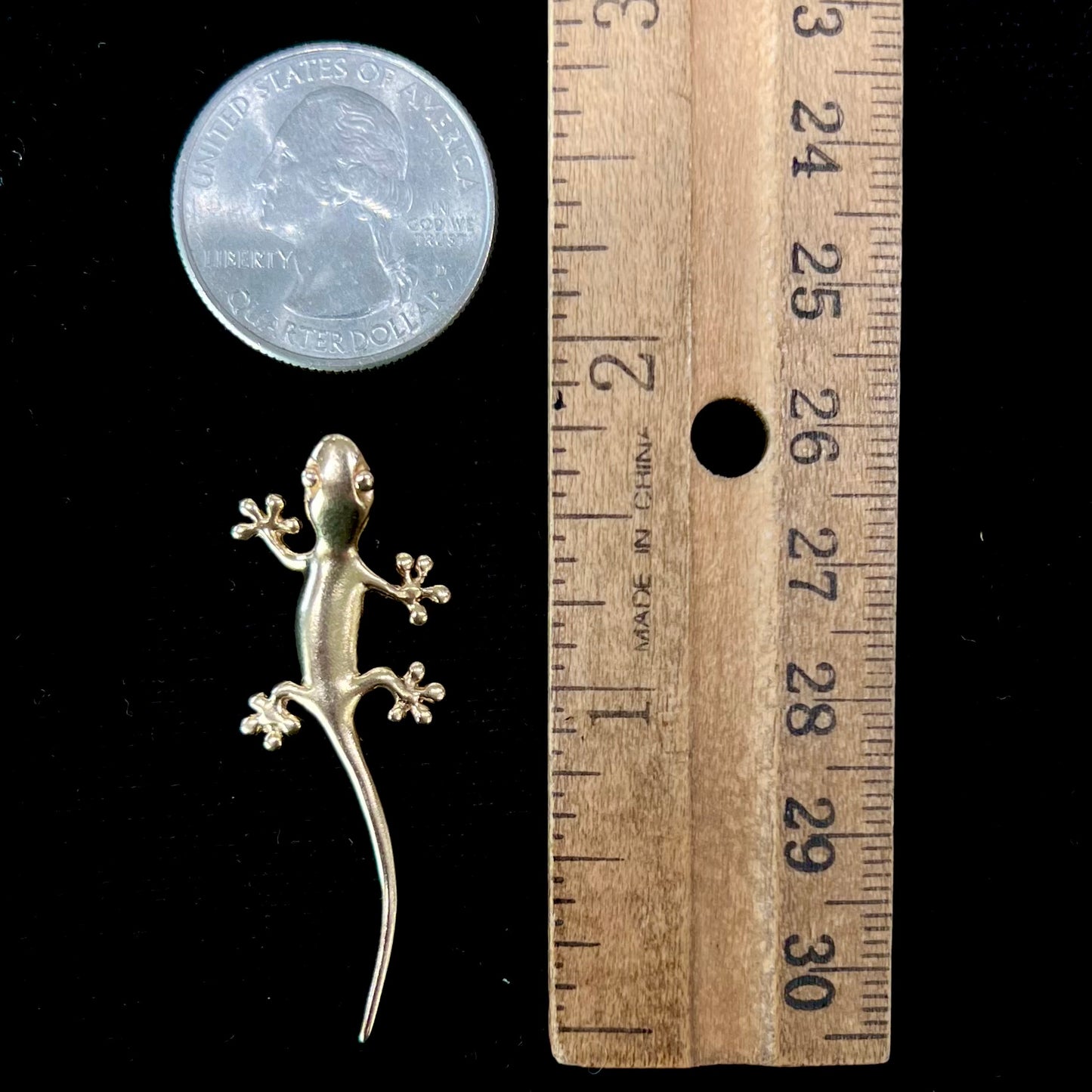 A solid yellow gold gecko lizard pendant with a hidden bail.