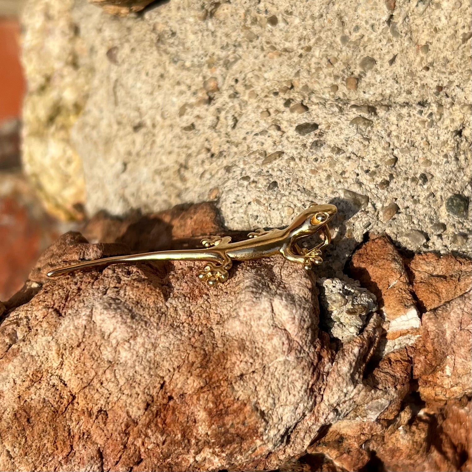 A solid yellow gold gecko lizard pendant with a hidden bail.