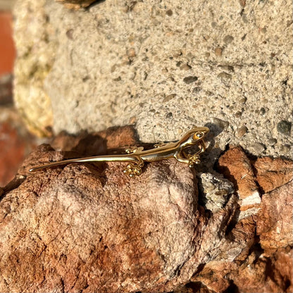 A solid yellow gold gecko lizard pendant with a hidden bail.