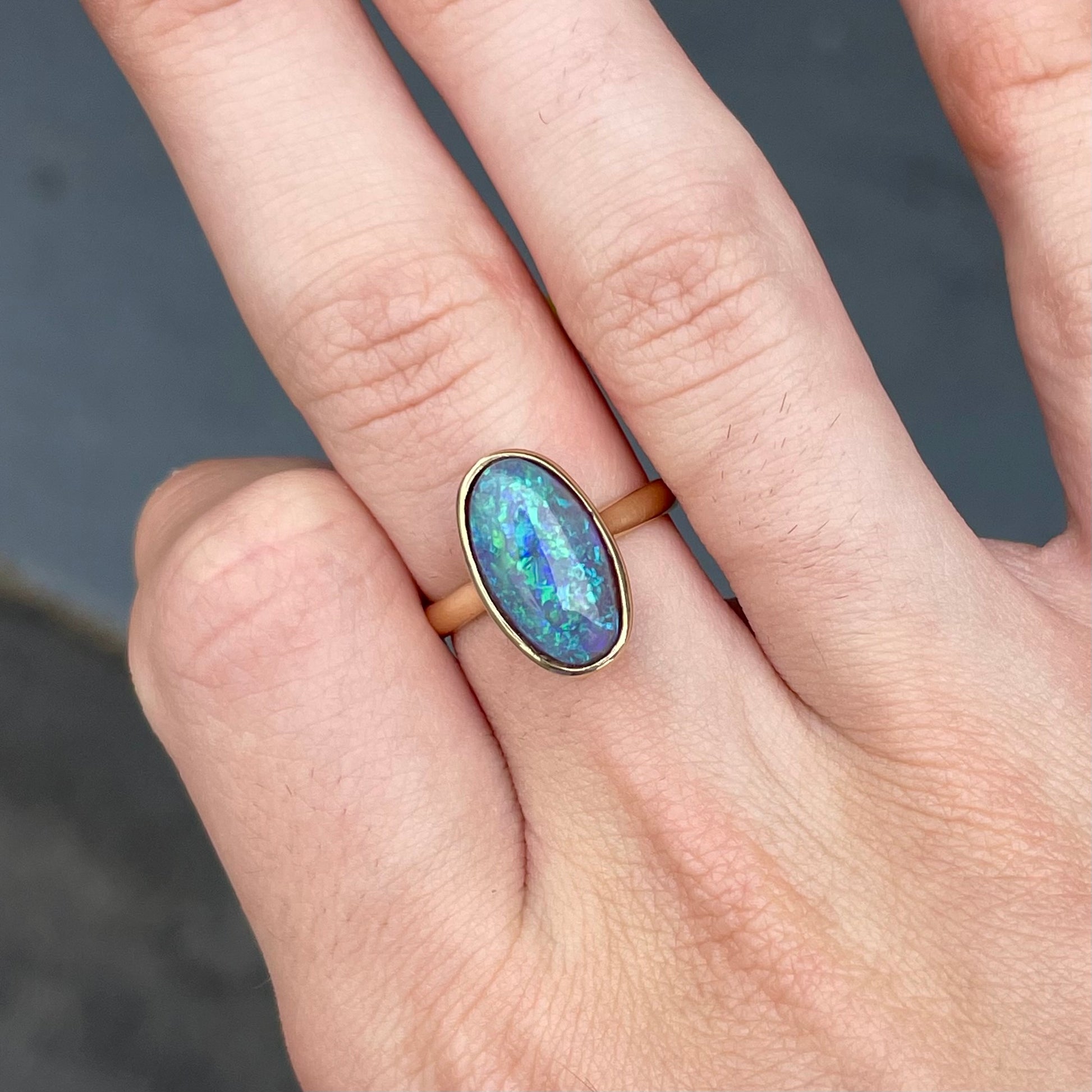 A simple yellow gold solitaire ring with a bezel set Lightning Ridge black crystal opal from Australia.