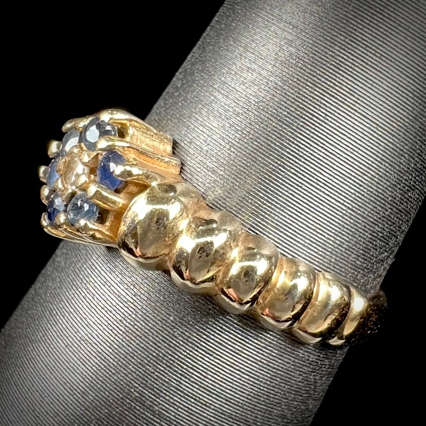 A ladies' yellow gold cluster ring set with round blue sapphires and a round diamond.