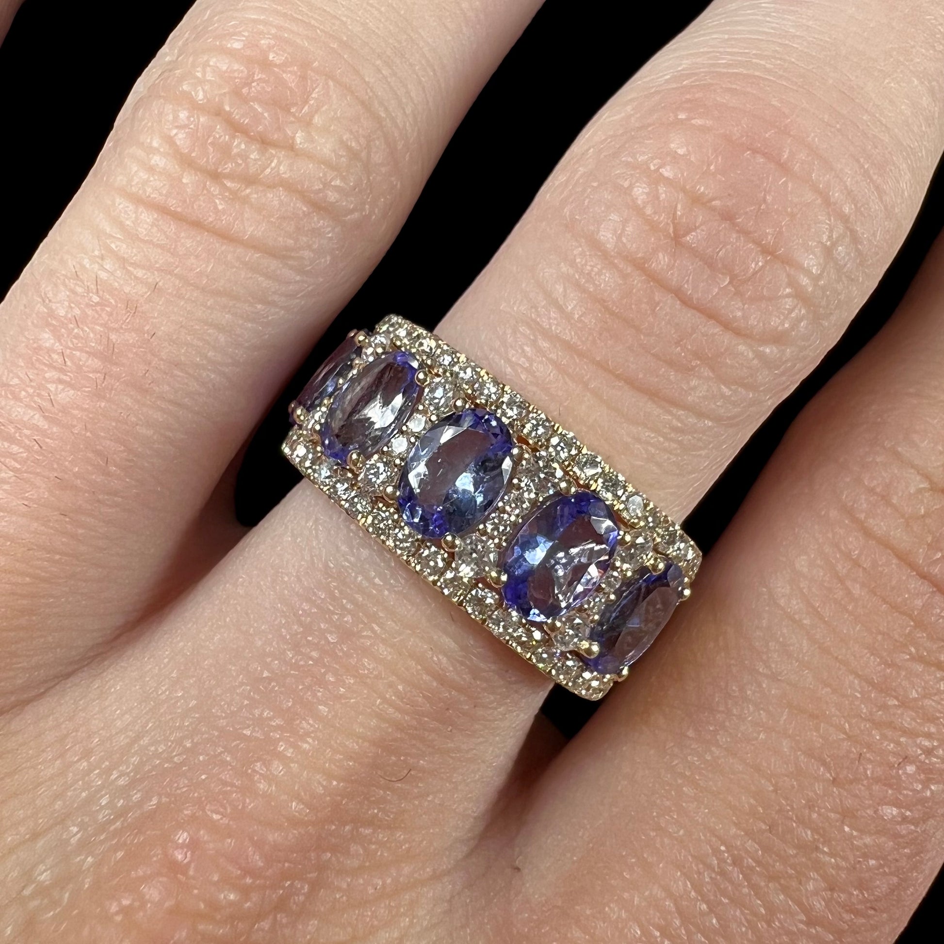 A gold and diamond ladies' band set with five oval cut tanzanite stones.