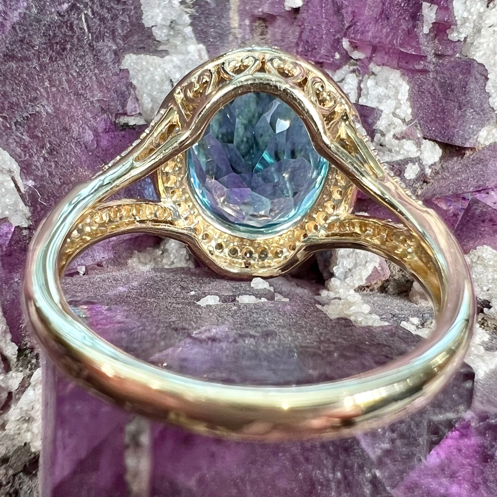 An oval cut Swiss blue topaz and diamond pave split shank ring in yellow gold.