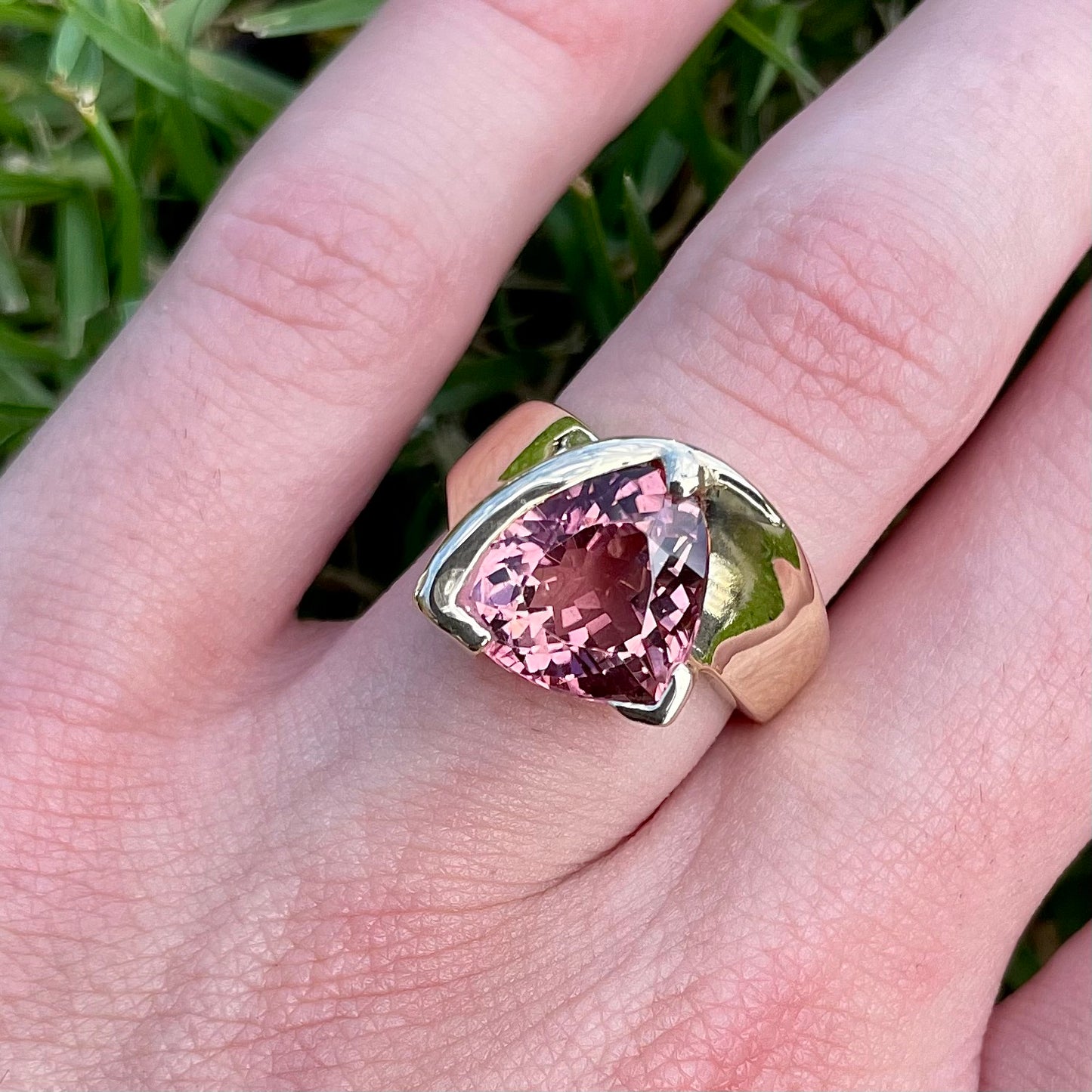 A unisex trillion cut pink tourmaline ring half bezel set in 14k yellow gold.