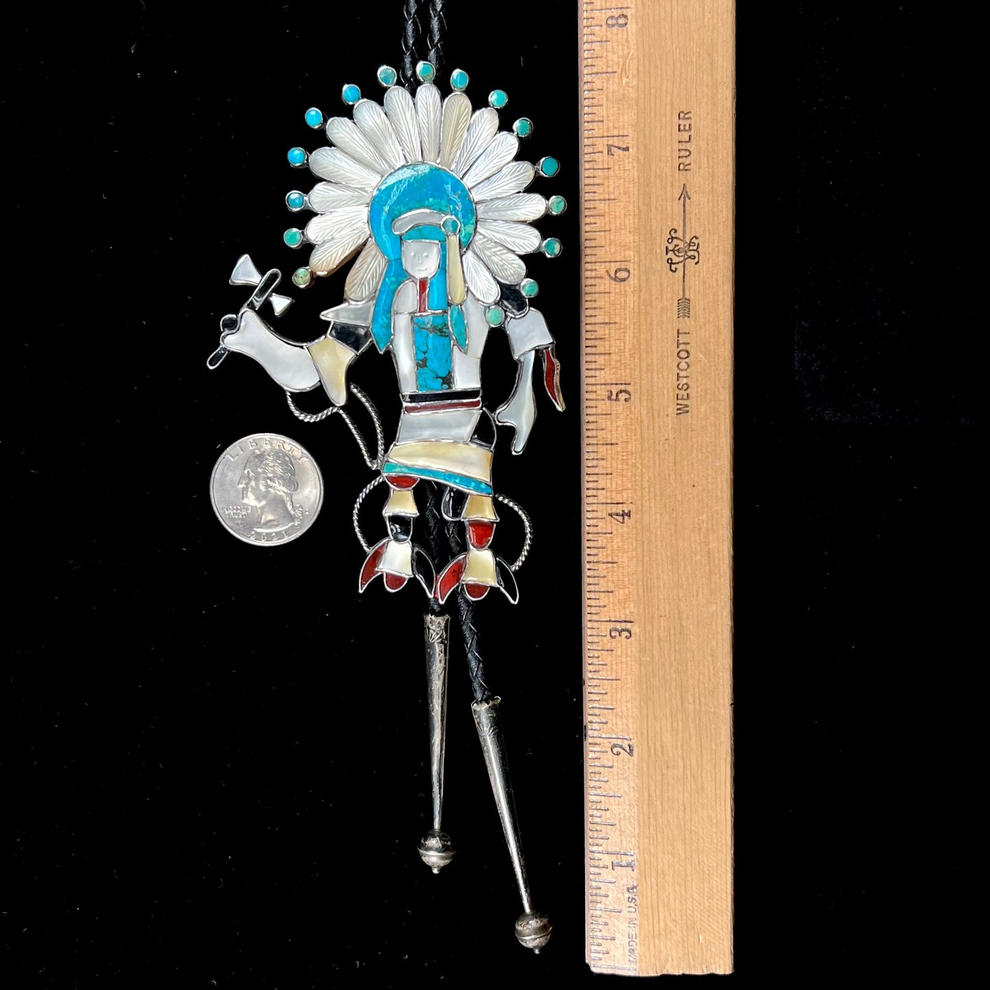 A Zuni Indian-made bolo tie featuring the motif of a kachina, inlaid with natural turquoise, mother of pearl, jet, and jasper stones.