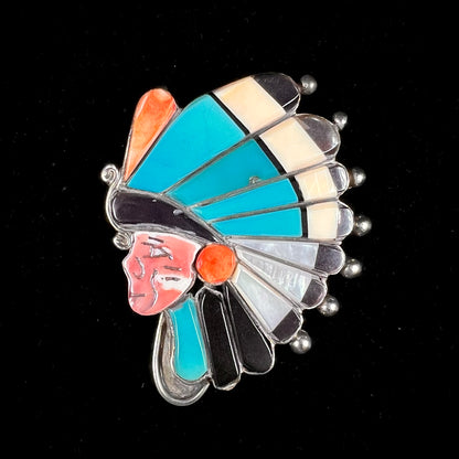 A Zuni Indian-made pendant featuring the motif of a chief inlaid with natural stones and shell.