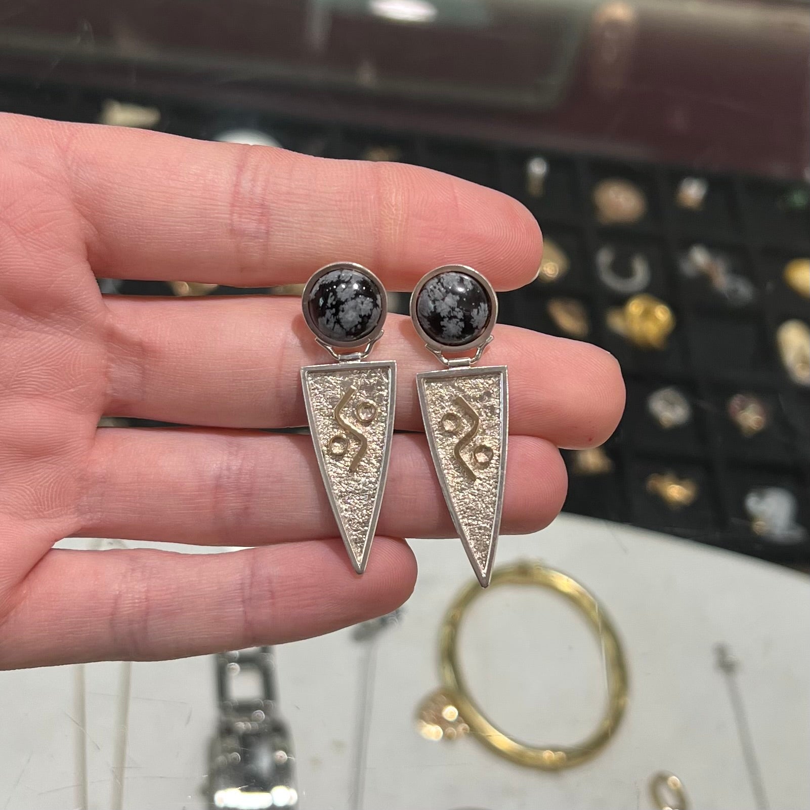 A pair of two-tone silver and gold snowflake obsidian earrings handmade by Zuni artist, Myron Panteah.