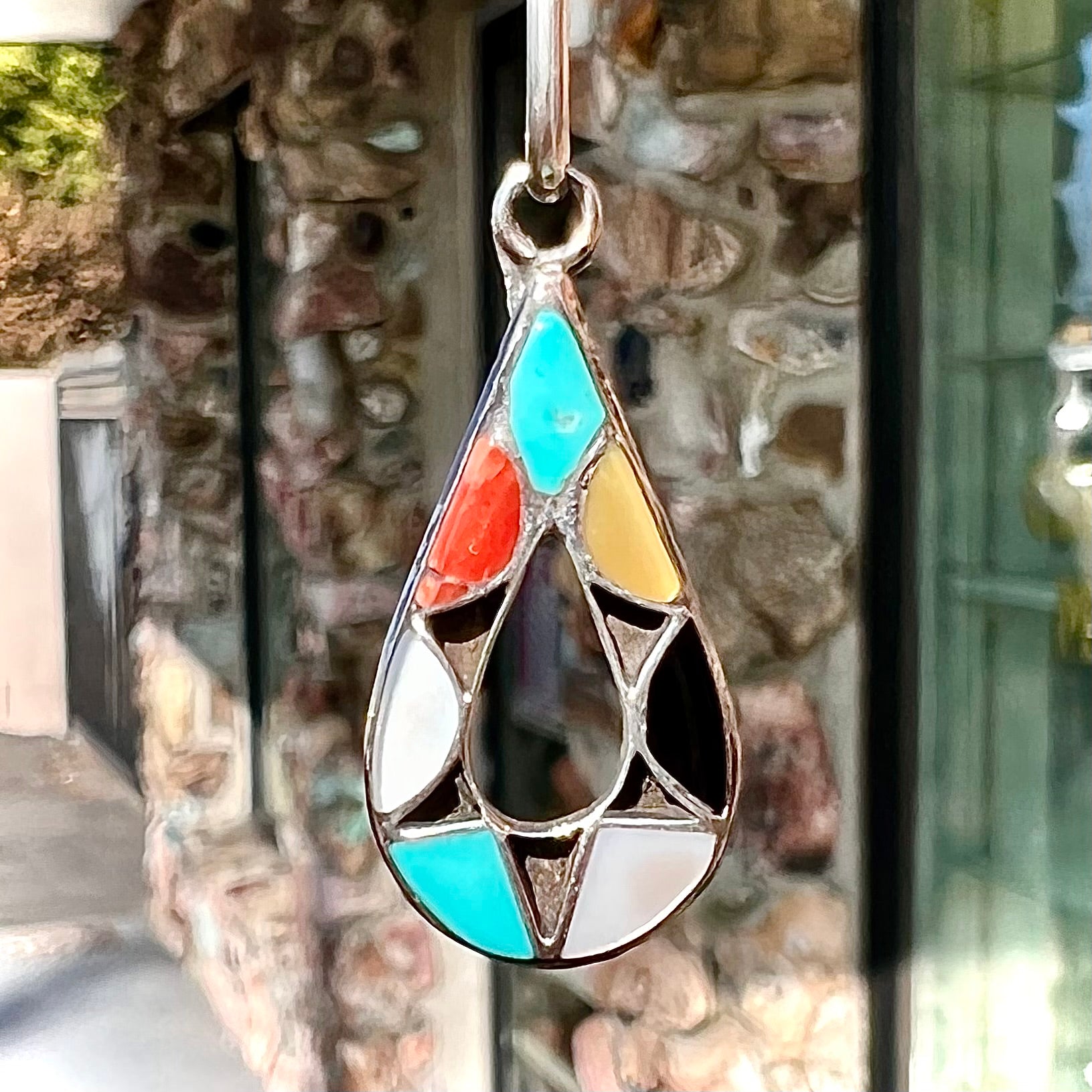 Photo of Zuni Indian pendant with stone inlay of coral, onyx, turquoise, jasper, and mother of pearl.