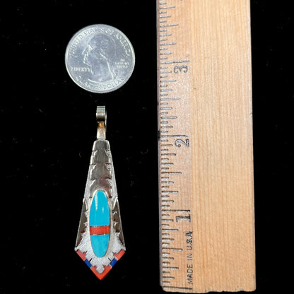 A yellow gold and sterling silver pendant inlaid with turquoise, coral, and lapis lazuli stones.  The piece is made by an unknown Native American artist and signed with the initials "LY".