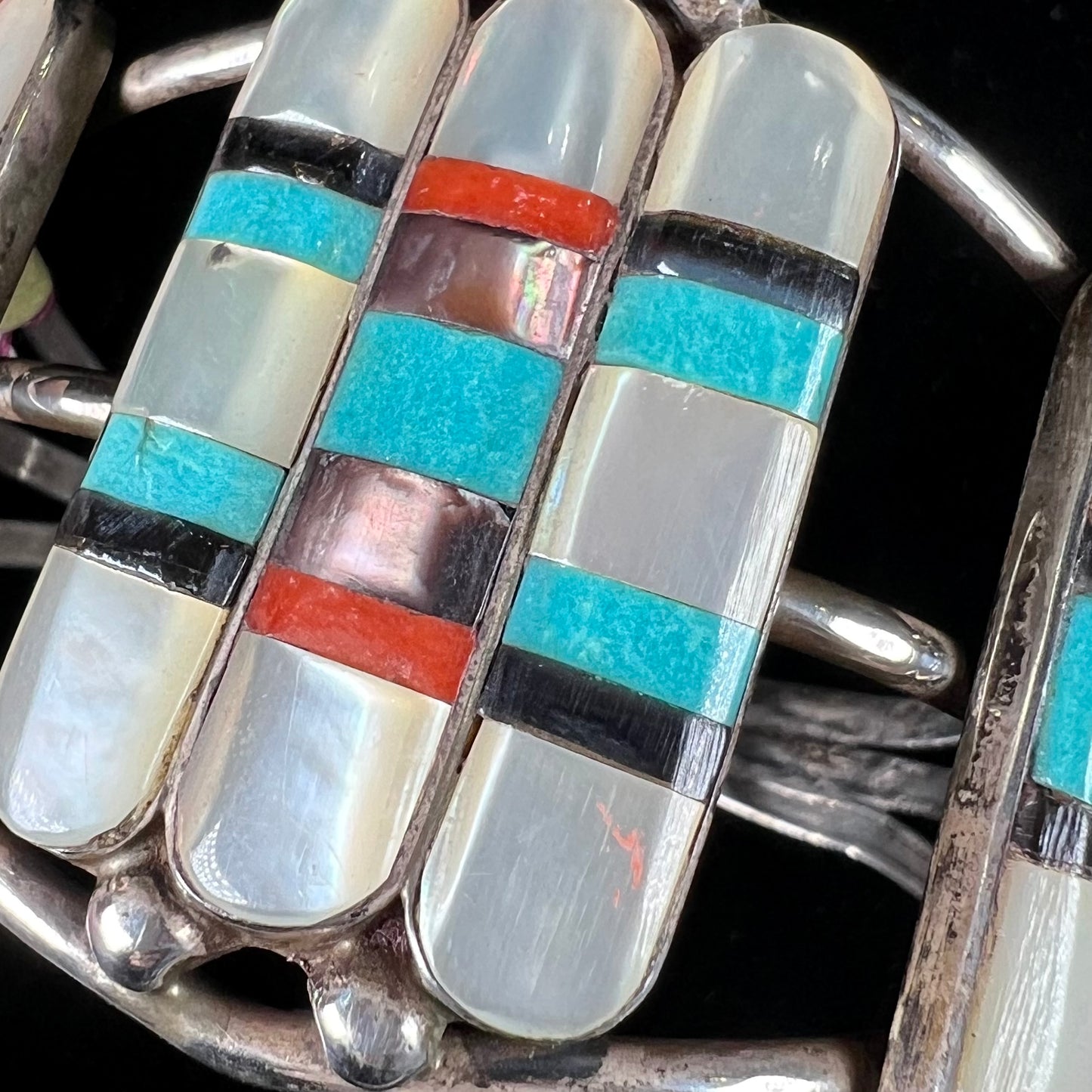 A vintage Zuni Indian-made inlay cuff bracelet set with mother of pearl, coral, turquoise, and jet stones.  The piece is signed "PONCHO."