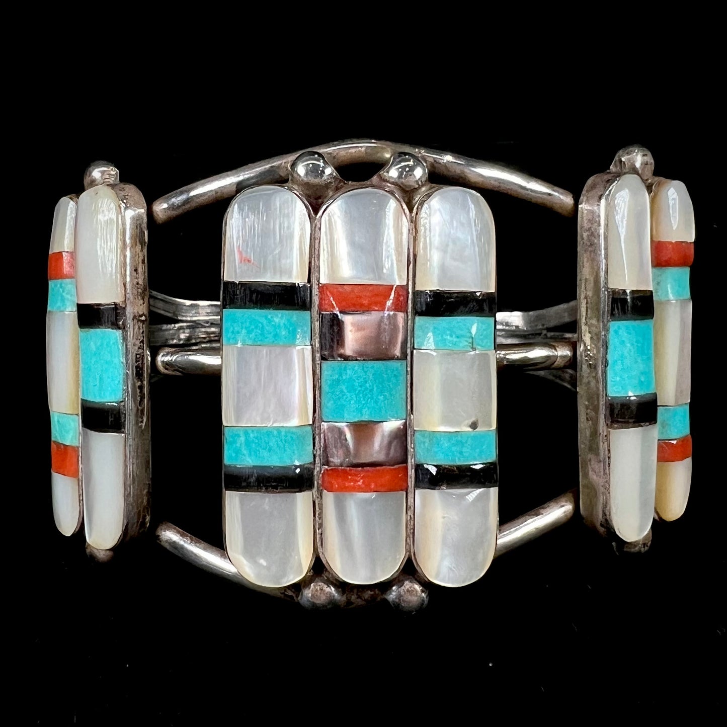 A vintage Zuni Indian-made inlay cuff bracelet set with mother of pearl, coral, turquoise, and jet stones.  The piece is signed "PONCHO."