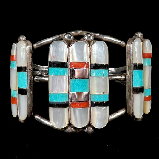 A vintage Zuni Indian-made inlay cuff bracelet set with mother of pearl, coral, turquoise, and jet stones.  The piece is signed "PONCHO."