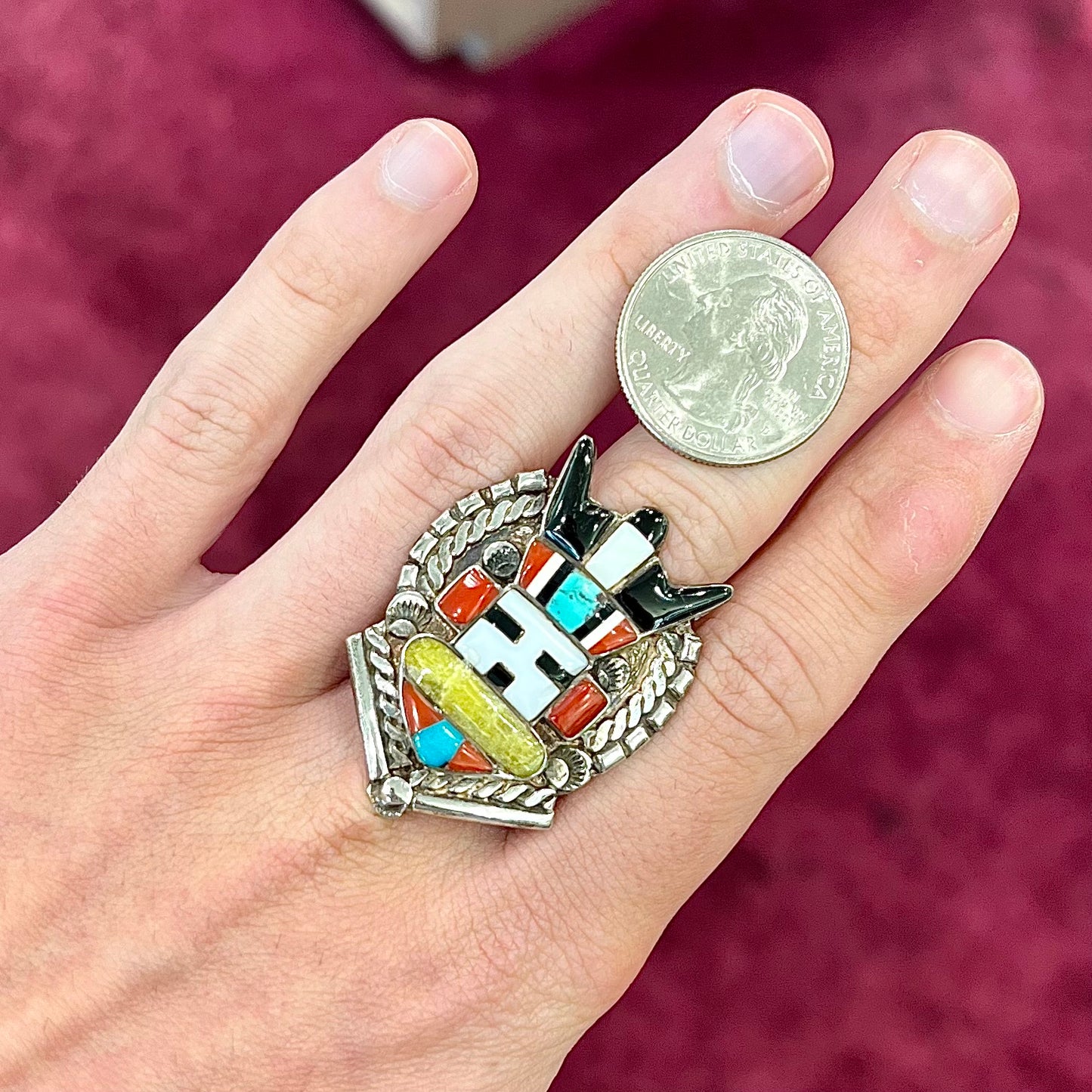 A sterling silver ring handmade in the motif of a Zuni Indian horned kachina set with onyx, turquoise, coral, mother of pearl, and sulfur quartz stones.