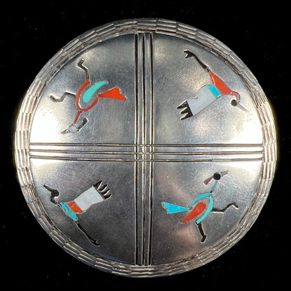 A silver pendant of two flying cranes and two roadrunners inlaid with turquoise, coral, and mother of pearl.