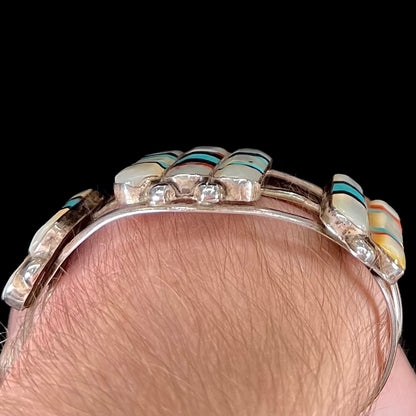 A vintage Zuni Indian-made inlay cuff bracelet set with mother of pearl, coral, turquoise, and jet stones.  The piece is signed "PONCHO."