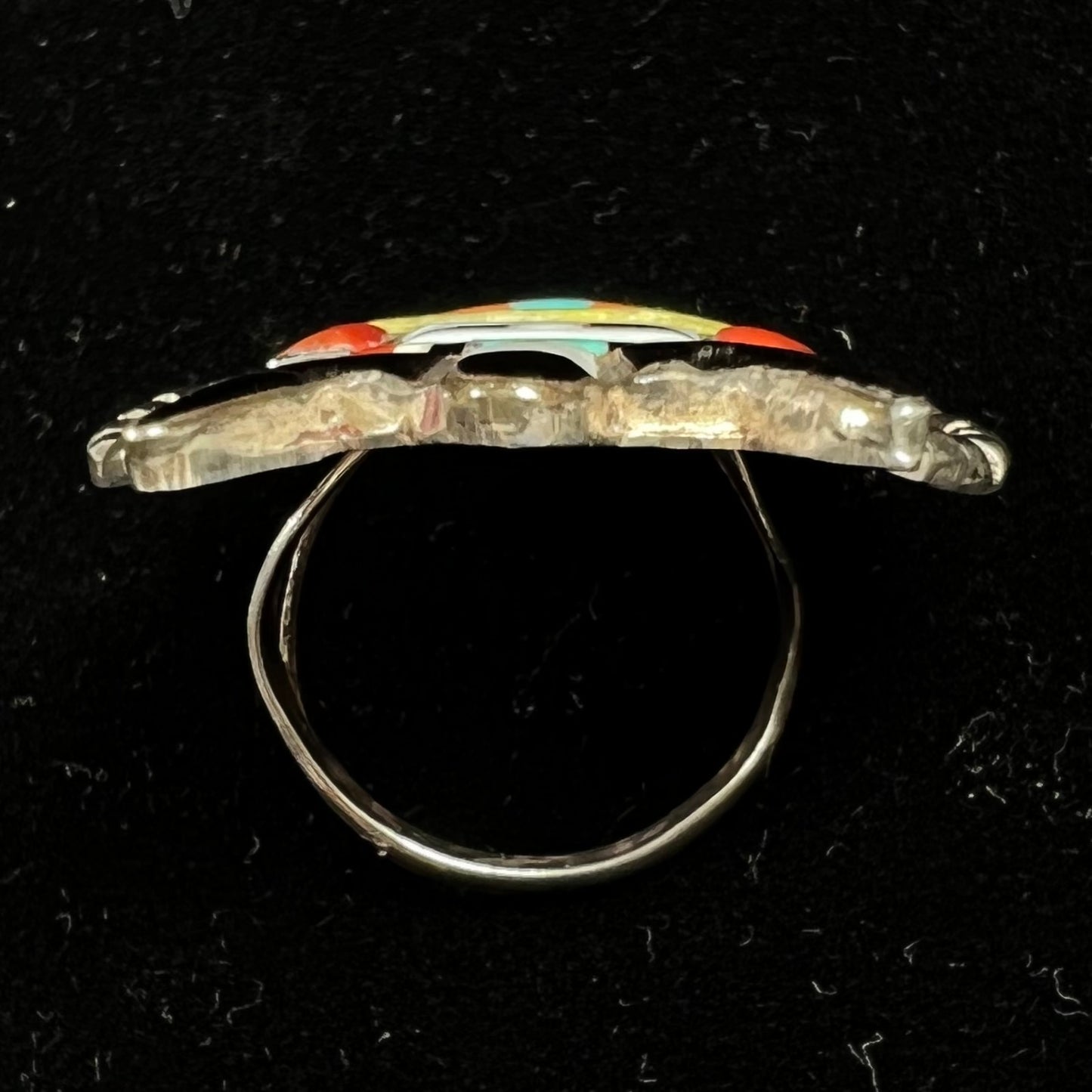 A sterling silver ring handmade in the motif of a Zuni Indian horned kachina set with onyx, turquoise, coral, mother of pearl, and sulfur quartz stones.