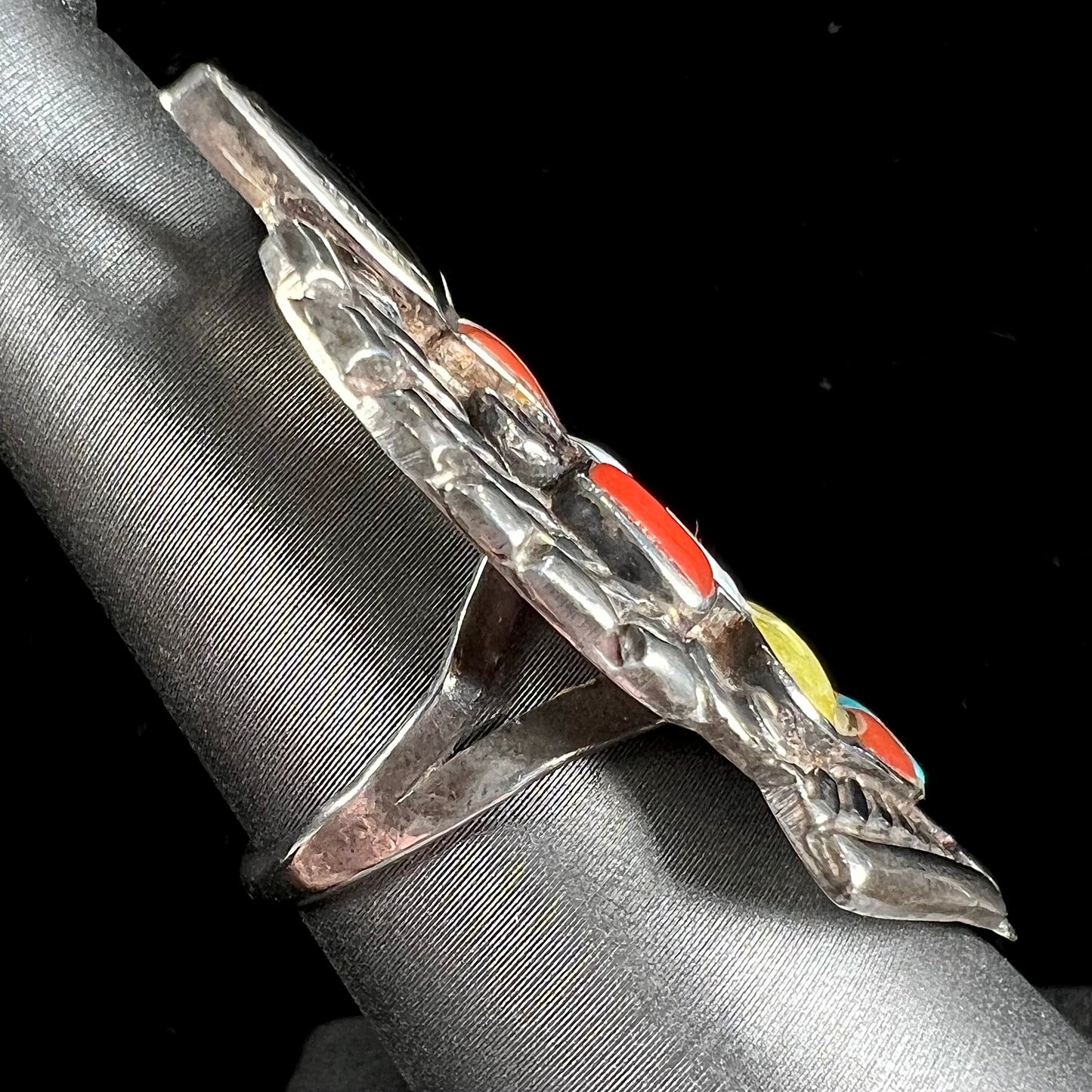 A sterling silver ring handmade in the motif of a Zuni Indian horned kachina set with onyx, turquoise, coral, mother of pearl, and sulfur quartz stones.