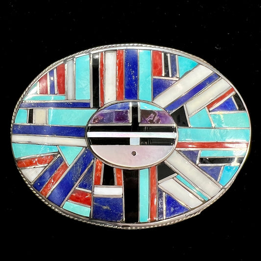 A sterling silver Zuni sunface belt buckle inlaid with lapis, turquoise, onyx, mother of pearl, coral, and sugilite stones.  It is stamped "RGB Zuni."