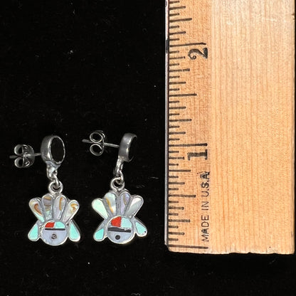 A pair of dangle earrings depicting the motif of Zuni Indian Sunfaces, inlaid with mother of pearl, onyx, turquoise, and coral.