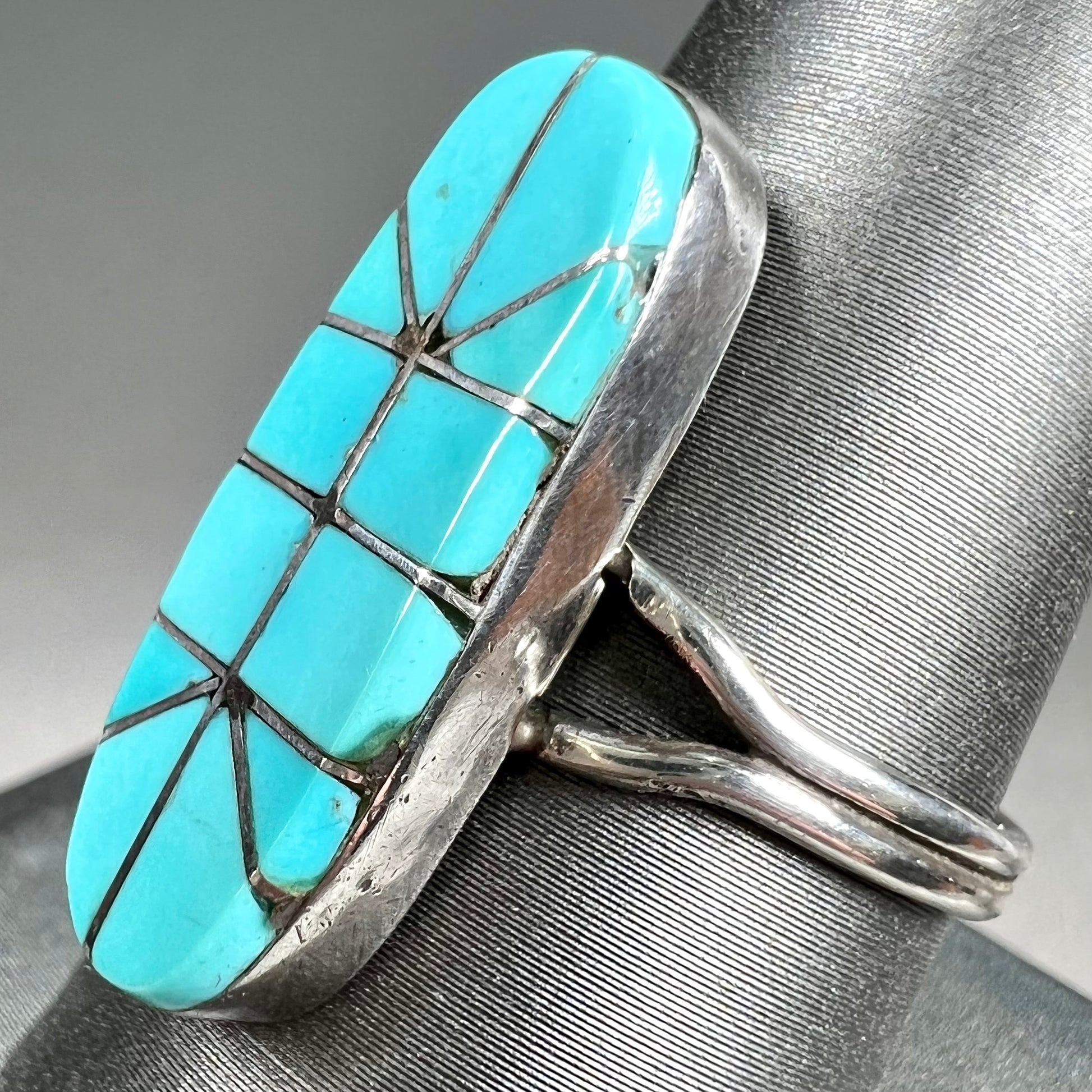 A handmade silver turquoise ring inlaid with six pieces of Sleeping Beauty turquoise.  The back of the ring is signed "FT".