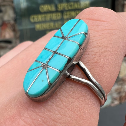 A handmade silver turquoise ring inlaid with six pieces of Sleeping Beauty turquoise.  The back of the ring is signed "FT".